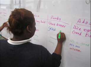 student facing a white board writing in a space that says "student goal".